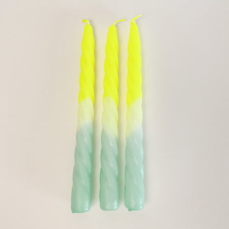 Set of 3, "Citron" Dip Dye Twisted Candles are hand dipped in a range of day glow yellow and aqua. An unexpected way to add festive color to your next table setting.  Hand dipped paraffin candles are made in collaboration with social institutions in Germany. Candles measure 9" length, 3/4" diameter. 