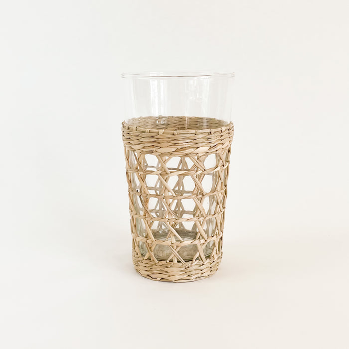 Seagrass cage highball glass is made from recycled glass and wrapped in a hand woven seagrass cage. Perfect for the natural table. Artisan made. Measures 6.25"H 3.25" D at mouth.