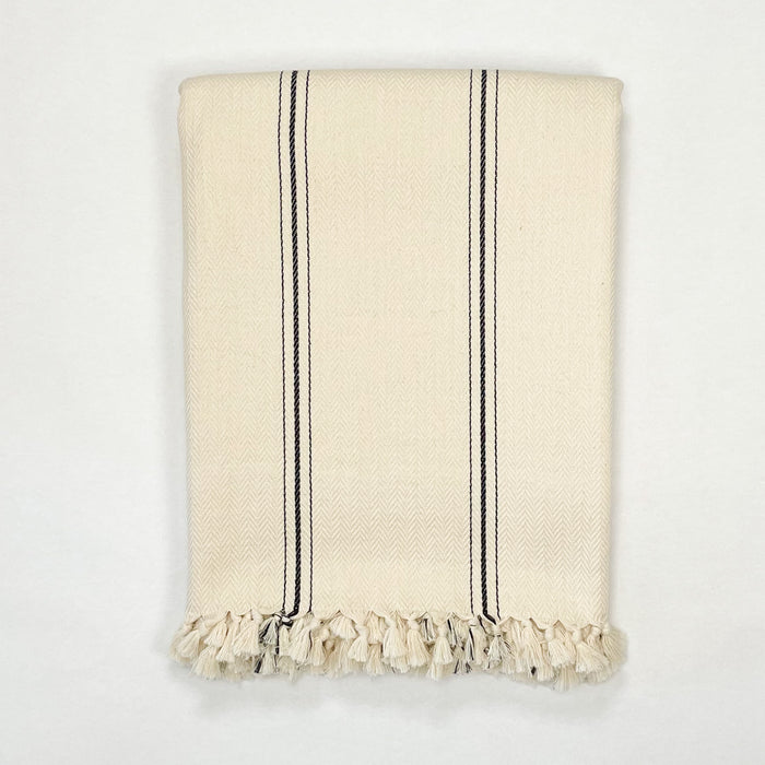 The Malibu Throw. Soft cotton throw that  suits classic, modern, farmhouse and boho decor with its versatile cream and black stripe pattern.  Hand knotted tassels finish off each side. Made in Turkey on traditional looms in a subtle herringbone weave. 100% cotton. Measures 65" x 85".