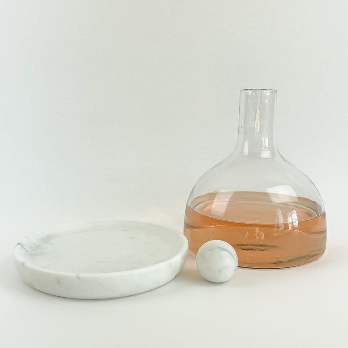 Glass + Marble Decanter. Chill the white marble tray in the freezer and use at the table to keep the contents of your carafe cool. Glass decanter, white marble tray and ball stopper included. Measures 7"H 6.25"D at base. Hand washing recommended.