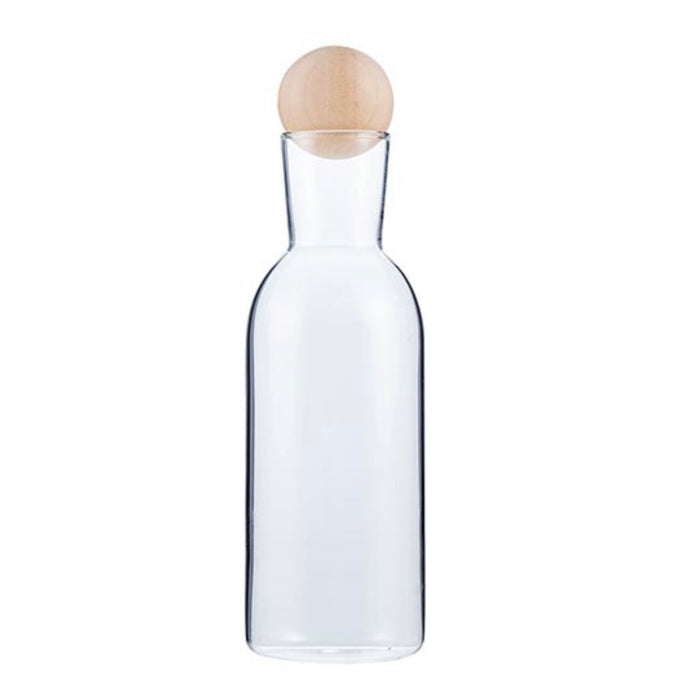 Oil + Vinegar carafe. Made of clear glass in a sleek modern silhouette and topped of with a natural wood ball stopper. Measures 7" H x 2" diameter. 
