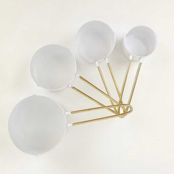 Set of 4 white enamel measuring cups with brass finished hair pin handle. Set includes 1 c, 1/2 c, 1/3c and 1/4 c. Bright and clean essential for the modern kitchen. 