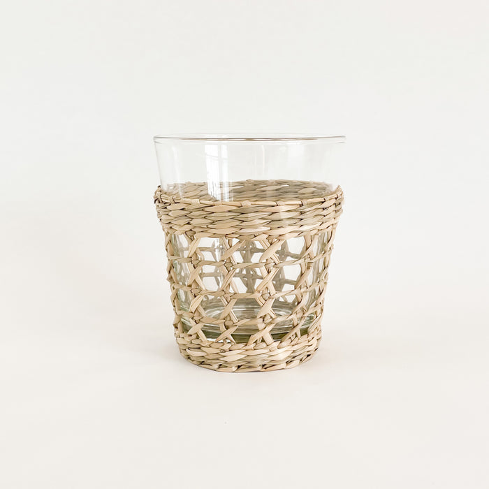 Wide seagrass tumbler. Made from recycled glass and wrapped in a hand woven seagrass cage. Measures 4.5" H 3.75" W at mouth. Perfect for the natural table.