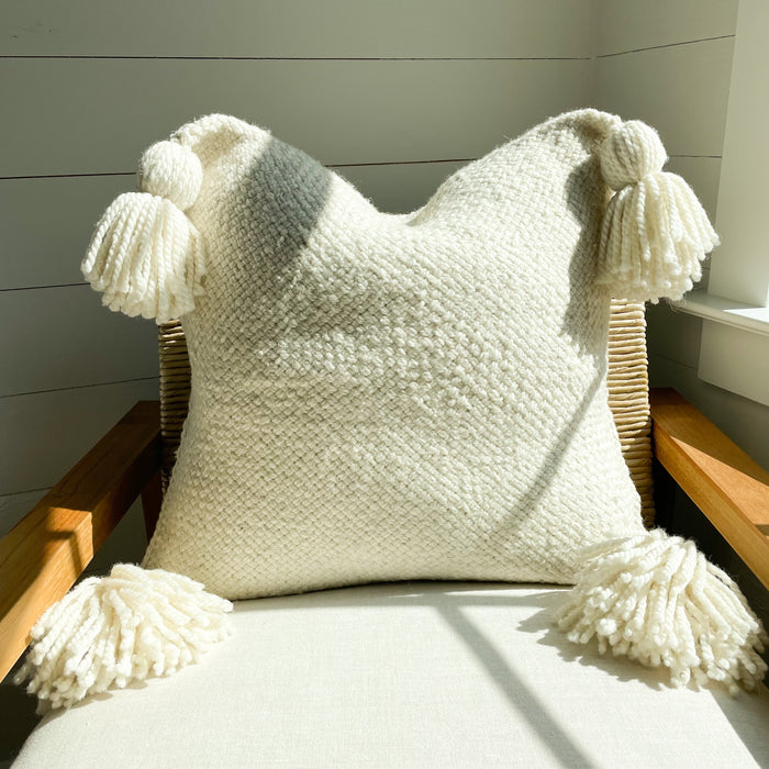 Layla Pillow cover. Warm natural texture hand made with thick cream wool yarn. Perfect for the modern boho home. Each corner is finished with a tassel. Tie back closure. Measures 20” x 20”.