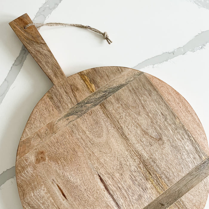 Close up view of the round rustic wood cutting board. Solid wood with horizontal inserts and jute rope hanging loop. Large size, 17" diameter 25" length 1" thick.
