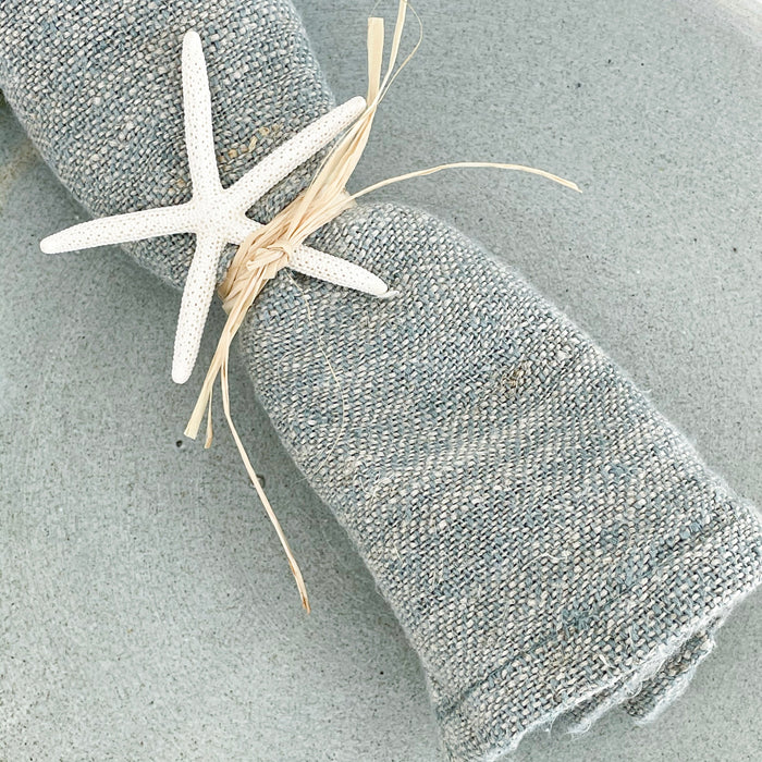 Close up of the texture of our Rustic Linen Napkins in dusty sea blue. 100% linen napkins measure 18" square. Styles with raffia and starfish, not included.