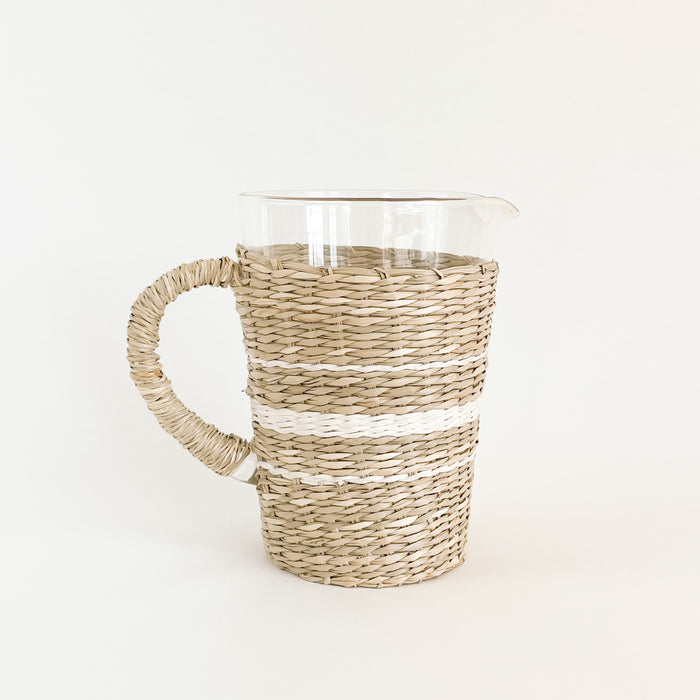 Hamptons Stripe Seagrass Pitcher. Recycled glass pitcher is wrapped in natural and white seagrass in a stripe pattern inspired by French linens. Perfect for the summer table. Measures 7.5" H 5"D at mouth and 4" D at base.