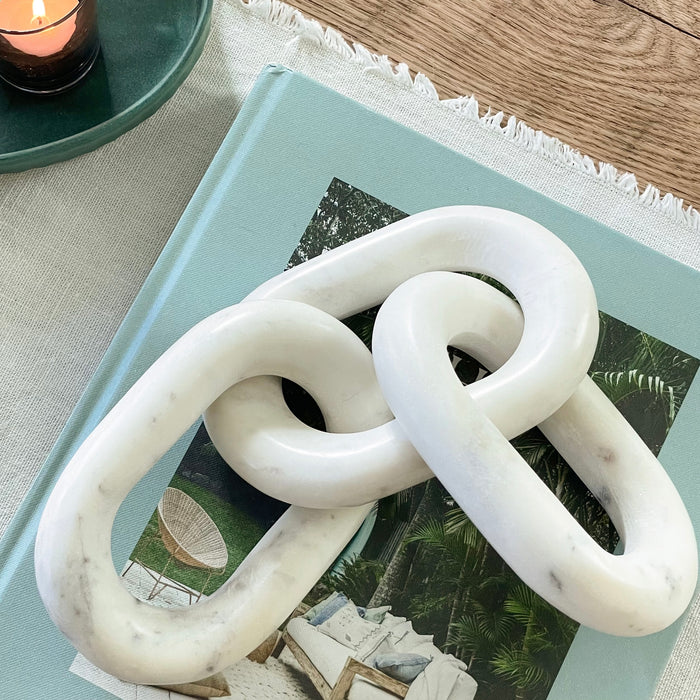 Marble Chain Link styled with a coffee table book adds sculptural interest. White marble with subtle grey veins. Measures 13" length total.