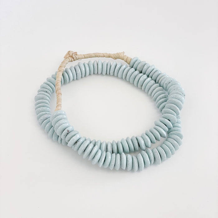 Pale Blue Ashanti beads make the perfect decorative accent in the modern coastal home. Hand made using traditional techniques in Ghana. Style them in a bowl or draped on the neck of a lamp. Approximately 26" length.