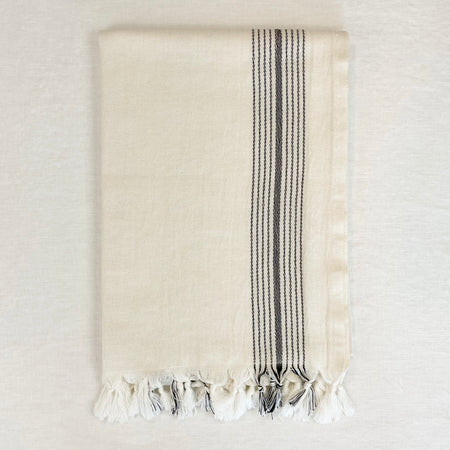 The Malibu Bath Towel is luxuriously oversized worthy of a spa. Measures 33" x 74"L. Made in Turkey on traditional looms in 100% cotton. Unbleached cream colored towel is framed with a cluster of thin black stripes on each side. Hand knotted tassels finish off the ends. 