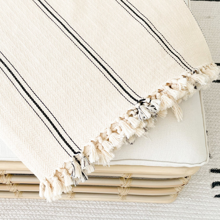 The Malibu Throw. Soft cotton throw features chic fine black stripes and mini hand knotted tassels at the end. A perfect layer to modern or bohemian decor.  Artisan made in Turkey on traditional looms in a subtle herringbone weave. Measures 65" x 85"