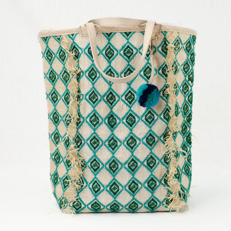 Jade and green beach tote embroidered with a diamond pattern. Natural leather handle and charm with green and blue pom pom.