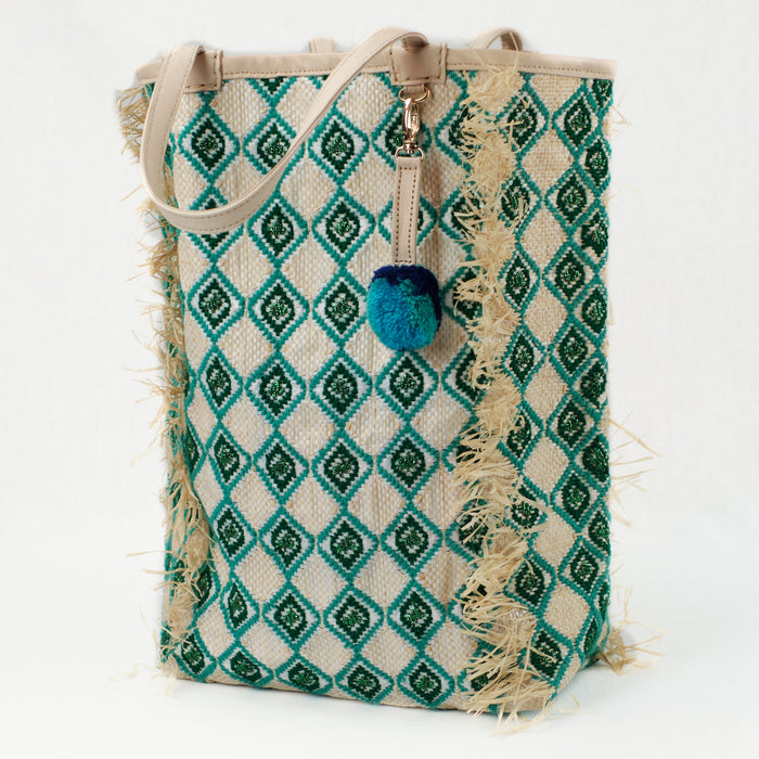Beach tote made from recycled grain bag and raffia with natural leather handles. Green and jade diamond pattern is embroidered all over bag with raffia fringe trim.