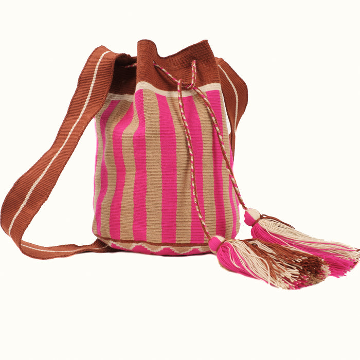 Soft woven bucket bag in fuchsia and tan stripes with a sepia and white strap. Drawstring closure is finished with fuchsia, tan & white tassels.