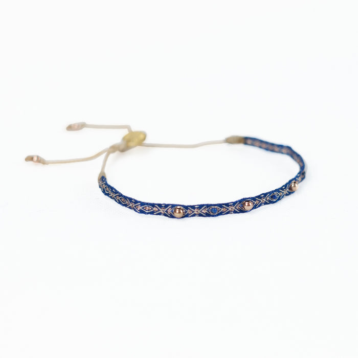 Deep azure blue woven friendship bracelet with brass beads and gold thread. Adjustable waxed cord for fit.