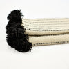Cream wool blanket with black stripes and black poms by Treko Wool.