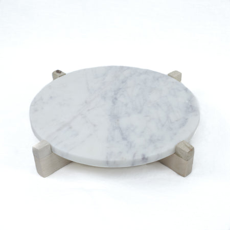 Small (11" D) round white marble serving board with natural wood stand. White marble with grey veining will vary slightly in each piece.