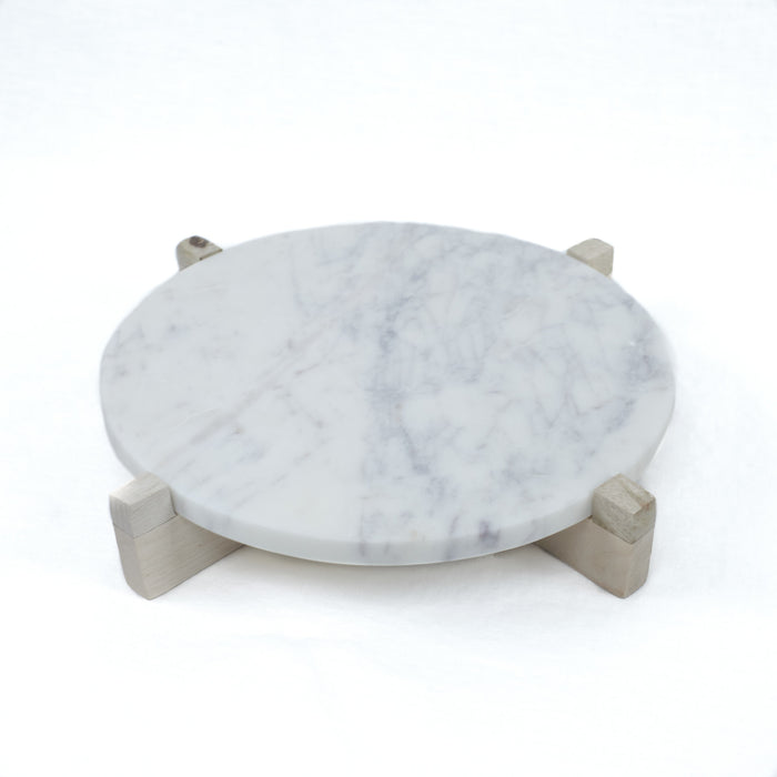 Small (11" D) round white marble serving board with natural wood stand. White marble with grey veining will vary slightly in each piece.