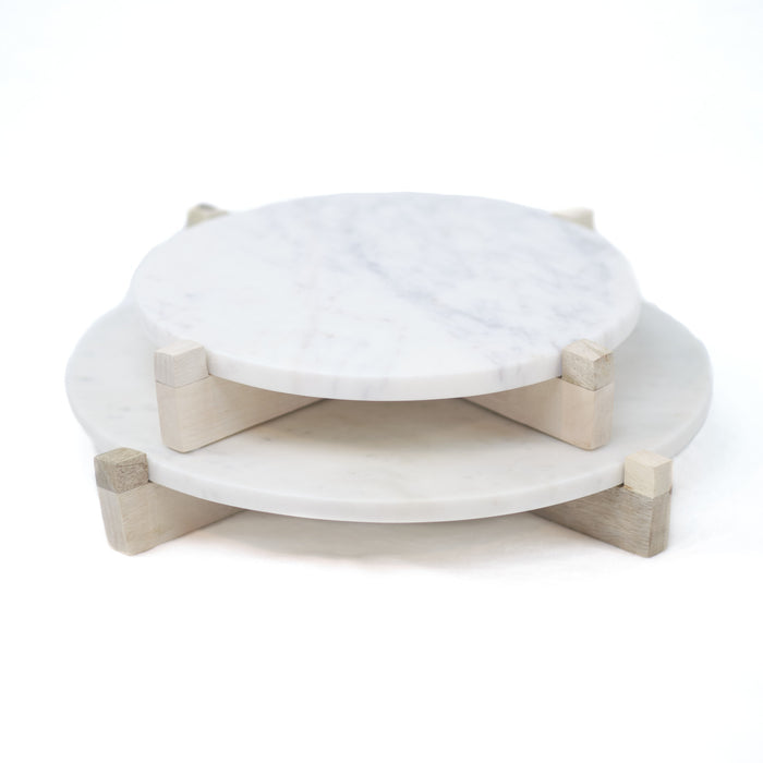 White round marble serving board with natural wood stand. Two sizes available, small 11" D and Large 14" D. Perfect for serving cheese or as a platform to keep kitchen necessities close at hand. Each sold separately.