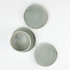 3 small ceramic plates with one bowl by Totem Home. Handmade ceramic pieces in blue-grey glaze.