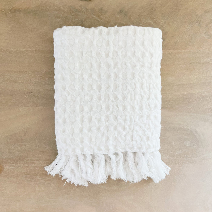 Alys waffle hand towel folded. White waffle weave cotton towel with hand knotted tassel ends. 21 x 32 inches.