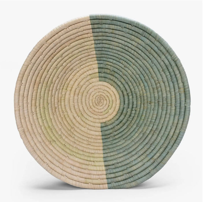 Seagrove basket bowl with a half and half color block in sea foam green and natural grass colors. Hand woven by artisans in Uganda using sweet grass and raffia fibers. 16" diameter.