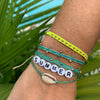 Wrist stack of the Gulf Green and Citron friendship bracelets shown with the summer shell bracelet. Each bracelet sold separately.