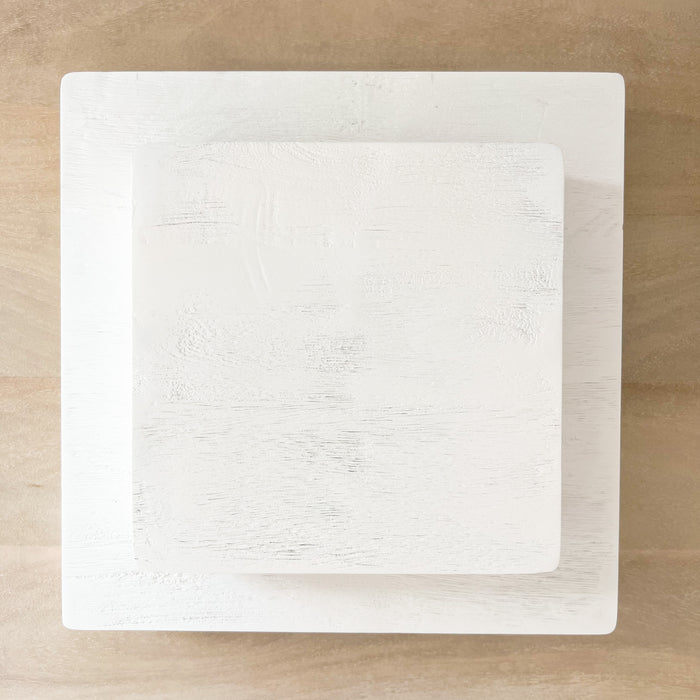 Stack of square, white, mango wood serving boards/risers. Glossy white finish shows the natural wood grain texture. Small and large shown, each sold separately.