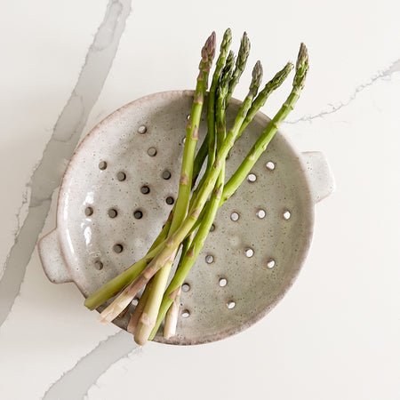 Ceramic berry bowl, shallow shape shown with two handles. Perfect for serving from garden to table with ease. Hand crafted ceramic, finished in a soft grey glaze with sandy speckles. Measures 8" diameter 2" high.