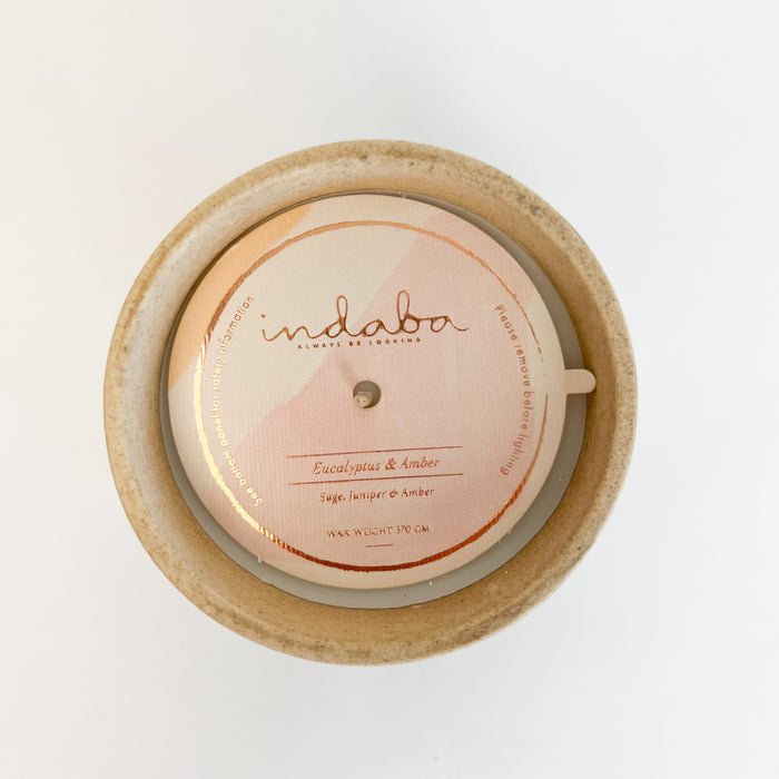 Eucalyptus and amber candle by Indaba. Scent of fresh eucalyptus with notes of sage, juniper and amber. Hand poured in a natural stoneware vessel. Two sizes available, each sold separately.
