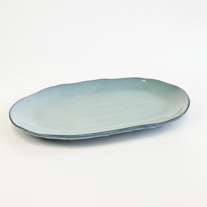 Azure ceramic platter finished in a glossy aquatic blue glaze. Perfect for summer entertaining and setting a coastal inspired table. Dishwasher and microwave safe. Measures 15" length, 9" width.