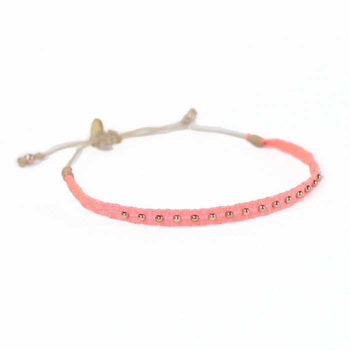Coral 9 friendship bracelet woven in a soft shade of coral pink and finished with tiny brass beads. Pull string adjuster, one size fits most.