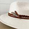 Roads Hat in ivory suede. Finished with a braided sepia brown suede strap and two small feathers.