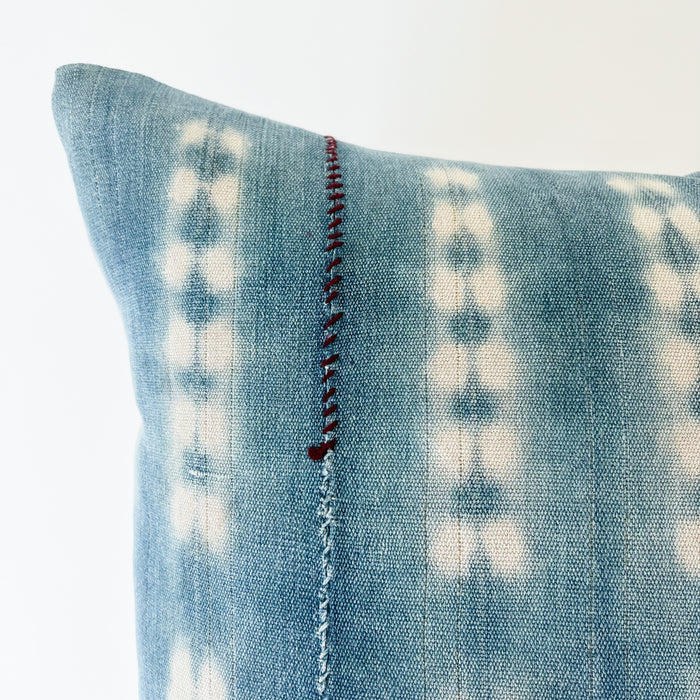 Close up detail of vertical hand mending in eggplant thread on pattern "shibori 2.0", square Zola pillow.