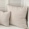 Palma Stripe Linen Pillow on a bench with another solid linen pillow. Each sold separately. Oatmeal and ivory stripe pillow. 27" square.