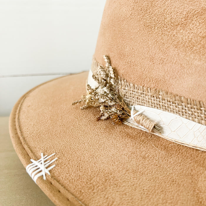 Close up detail of the sprig of dried wild flowers on the Sparkles Hat. Light camel suede hat with burlap and ivory snakeskin strap.