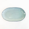 Azure ceramic platter finished in a glossy watery blue glaze. Perfect for setting a coastal inspired table and summer entertaining. Dishwasher and microwave safe. Measures 15" length, 9" width.