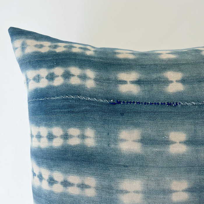 Close up detail of horizontal hand mending in bright blue thread on pattern "shibori 1.0", square Zola pillow.