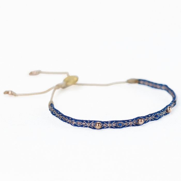 Azure 2 woven friendship bracelet in a rich shade of blue with fine gold embroidery and embellished with brass beads. Pull string adjuster, one size fits most.