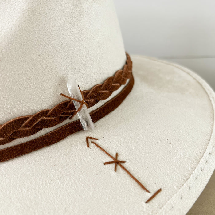 Roads Hat made in ivory suede. Finished with a braided suede strap and a clear crystal. Hand stitched boho arrows on the brim and front of hat.