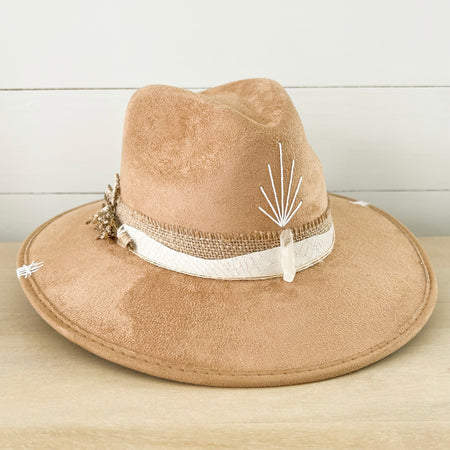 Sparkles Hat made in light camel suede. Crown is wrapped with a burlap and white snakeskin strap. Finished with a sprig of dried wild flowers, a clear crystal and hand stitched details on crown. Measures 58cm/22" around crown.