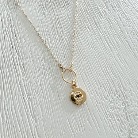 Eye on You necklace. 14K gold filled chain holds a small gold plated evil eye charm with a blue stone in lay. Hand made in the U.S. by Kozakh. Chain length is adjustable 16 to 18 inches.