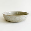 Stoneware Bayside serving dish. Finished in a fog grey glaze with sandy speckles. The organic texture makes it the perfect accent for the coastal table. Ideal size for a serving of pasta or buddha bowl. 10.5" diameter, 2.75" height.