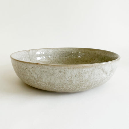 Stoneware Bayside serving dish. Finished in a fog grey glaze with sandy speckles. The organic texture makes it the perfect accent for the coastal table. Ideal size for a serving of pasta or buddha bowl. 10.5" diameter, 2.75" height.