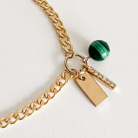 Etain charm bracelet. Flat 14K gold filled chain features a hand carved green Malachite sphere and a cubic zirconia encrusted charm. Adjustable length, 6 to 7 inches.