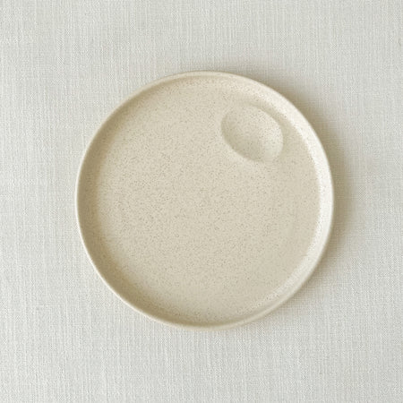 Large Mesa stoneware plate. Small batch stoneware made in Portugal. Hand formed dimple for creating an artful presentation with a sauce. Modern, high rim silhouette finished in a creamy matte white glaze. 9.75" diameter.