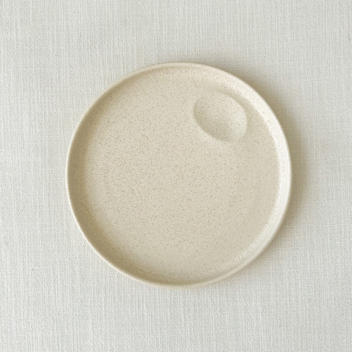 Large Mesa stoneware plate. Small batch stoneware made in Portugal. Hand formed dimple for creating an artful presentation with a sauce. Modern, high rim silhouette finished in a creamy matte white glaze. 9.75" diameter.