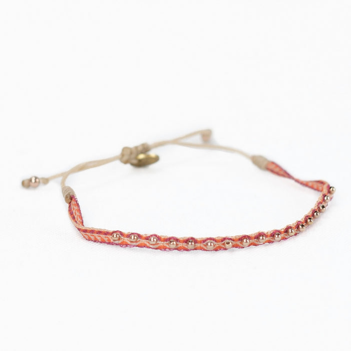 Guava 7 friendship bracelet woven in shades of fuchsia and orange with fine embroidery and embellished with tiny brass beads. Pull string adjuster, one size fits most.