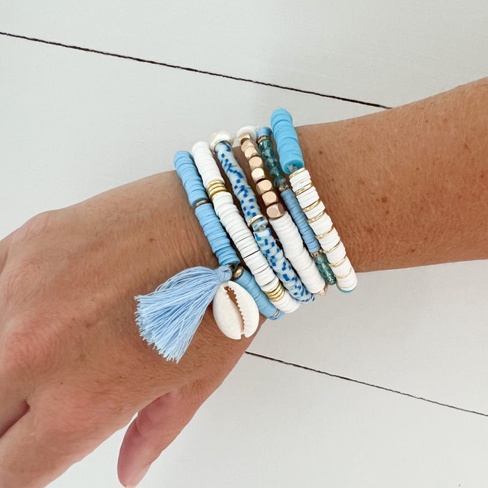 Set of 6 stretch heishi surf bracelets in blue, white and gold. Stack them or wear them individually for coastal surf style. Stretch bracelets, one size fits most.