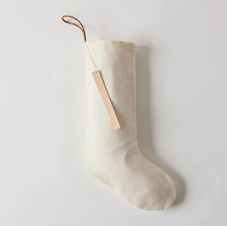 Ivory linen Christmas stocking with cotton lining. Natural leather hanger loop. Hand stamped leather tag "Merry". 